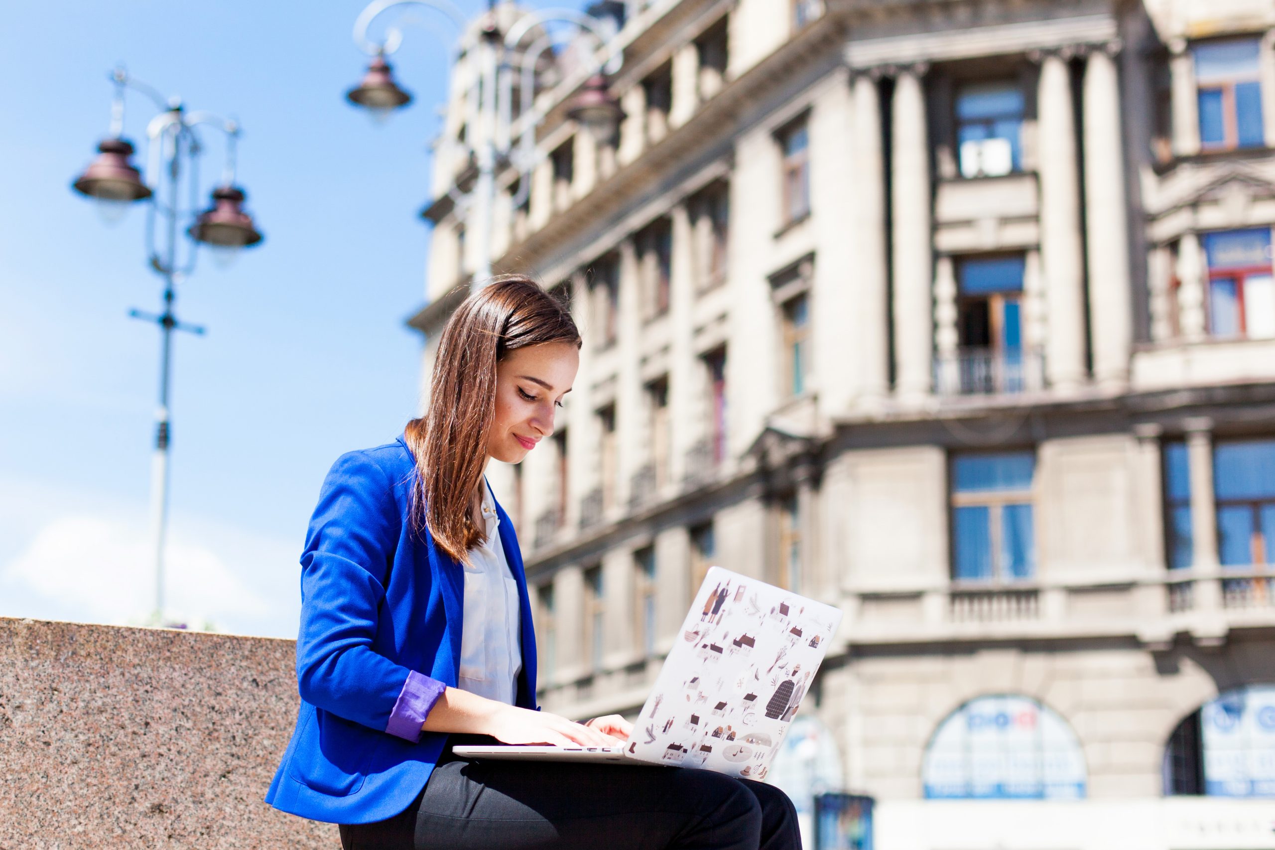 Woman sits on the street and works with a laptop